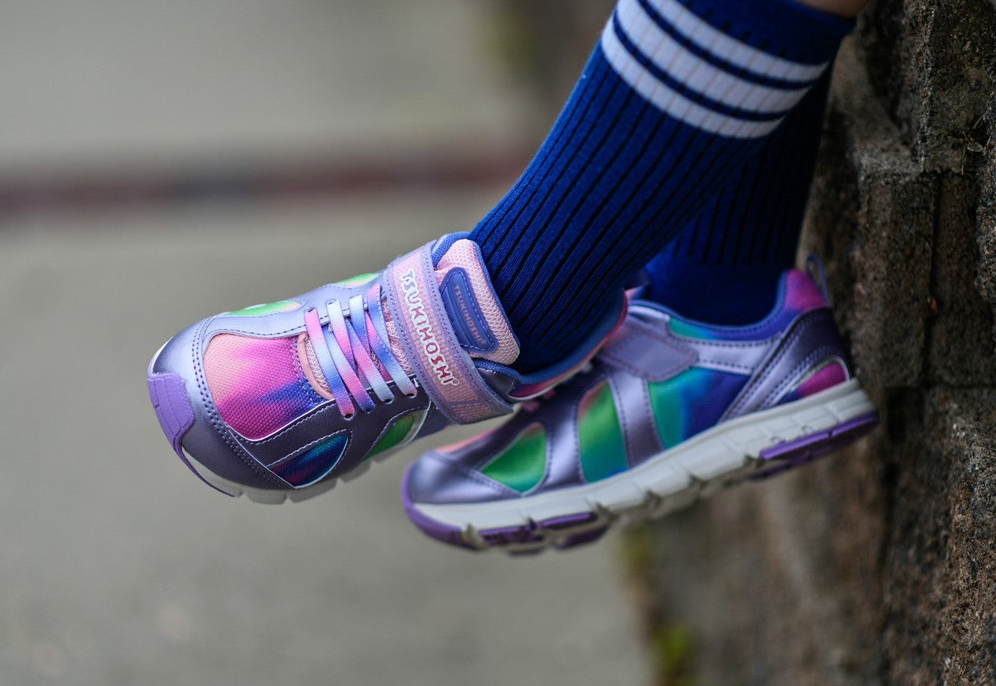 A close-up of a little kid wearing the Tsukihoshi Rainbow sneakers with knee high socks